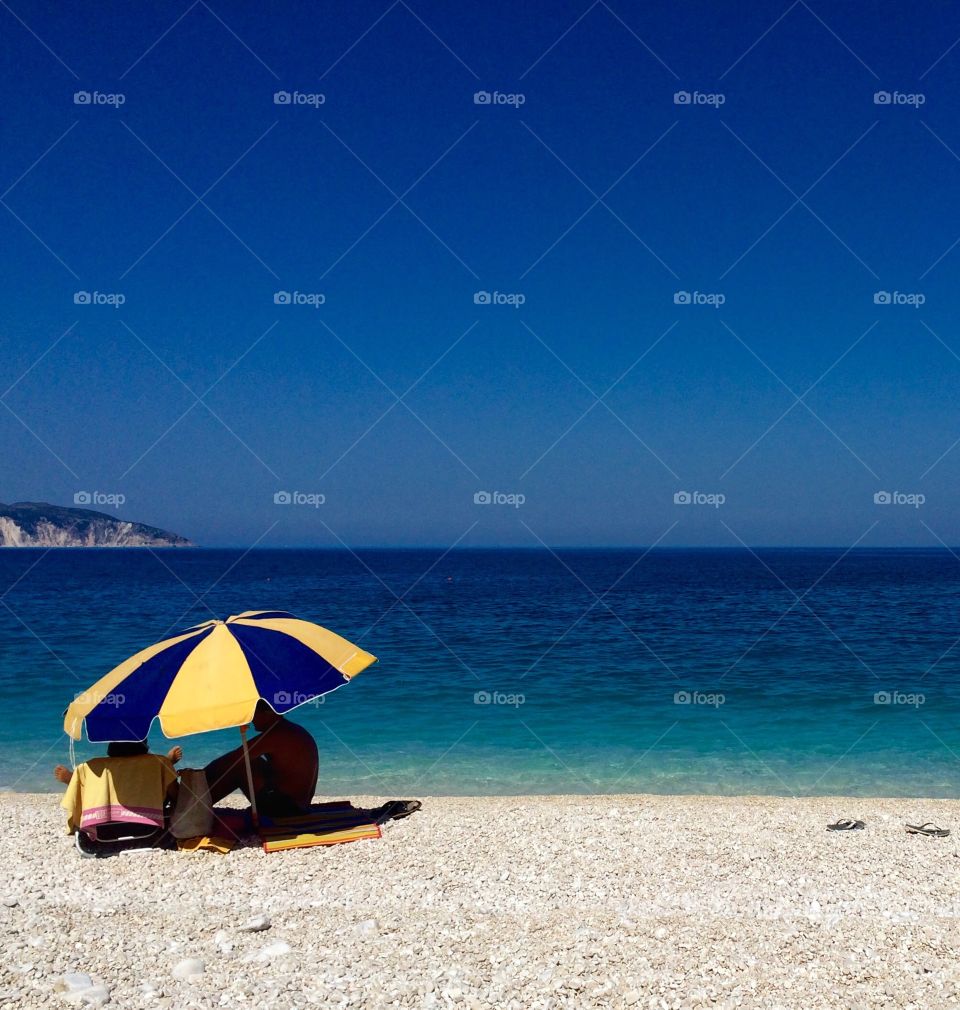 Summertime in Kefalonia ... seeking some shade under a parasol ... love the three blues in this photo and the discarded flip flops just to the right of the image and the casting shadow ... hope you like it too 💙