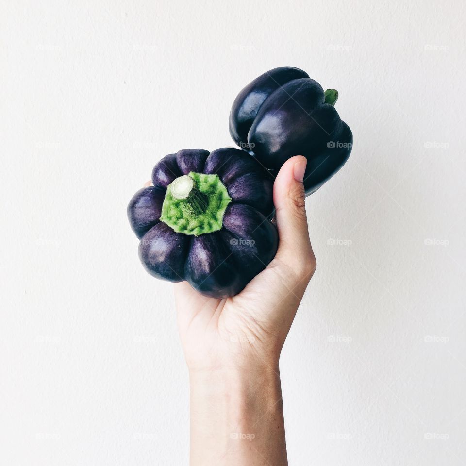 Person holding purple bell peppers