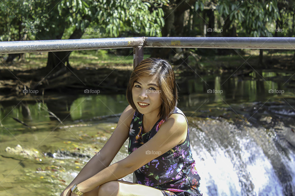 Asean woman and water in the stream is green and bright green tree at Kapo Waterfall Fores Park , Chumphon in Thailand.