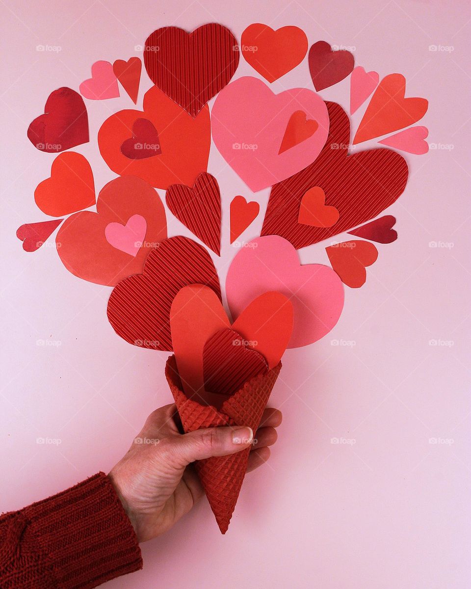 Hand holding cone with many paper hears.