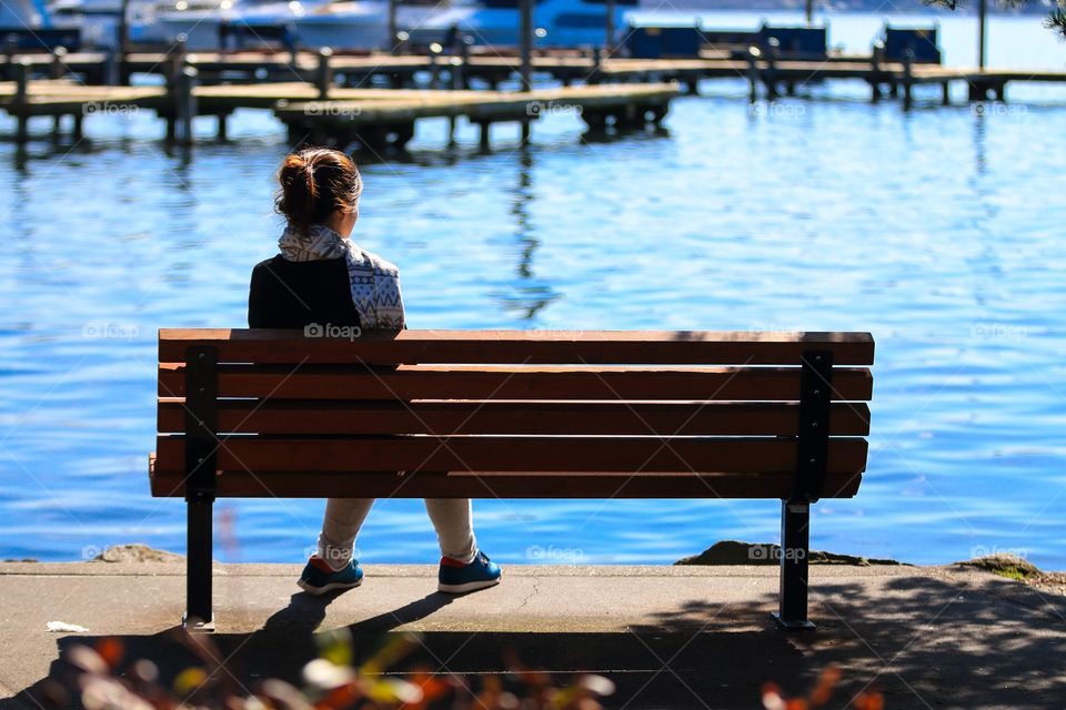 Girl sitting alone on the chair near the coast 