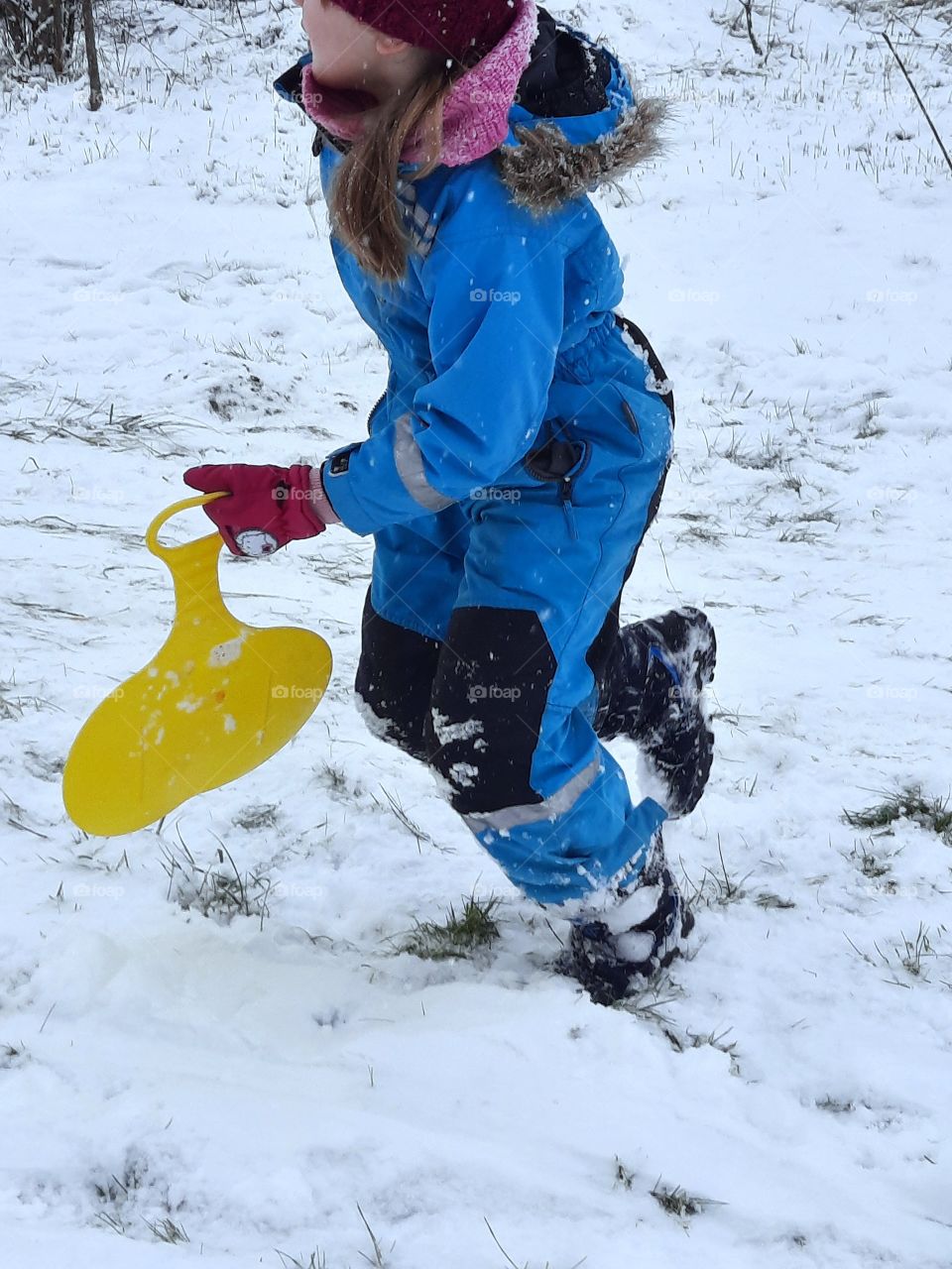 child running up-hill enjoying snow and sliding