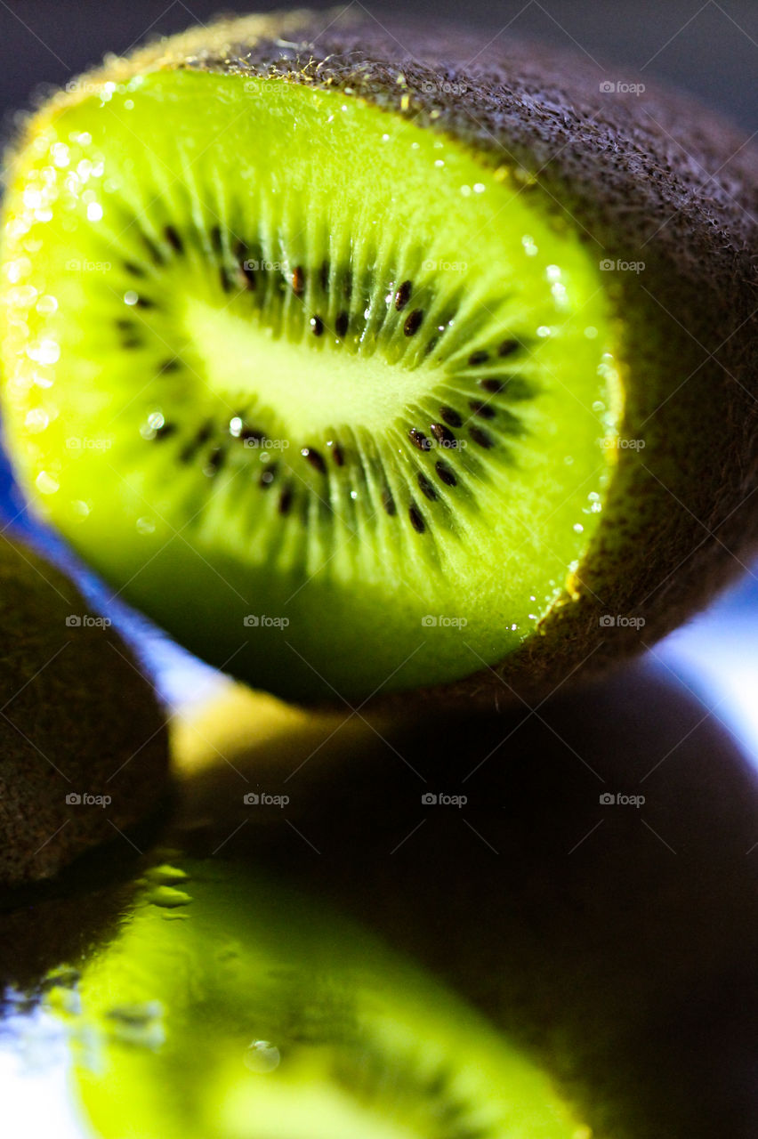  Macro of a cut ripe Kiwi fruit on a mirror. Kiwi is a berry because it is a single fleshy fruit without a stone & contains seeds. The Kiwi grows on a vine & is also called a Chinese gooseberry or the Chinese name of origin, mihoutau. 
