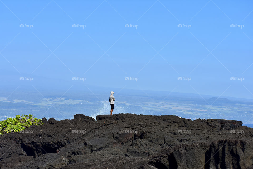 Watching the surf with the volcano in the distance on a beautiful day at Richardson Ocean Park in Hilo, On the Big Island of Hawaii.