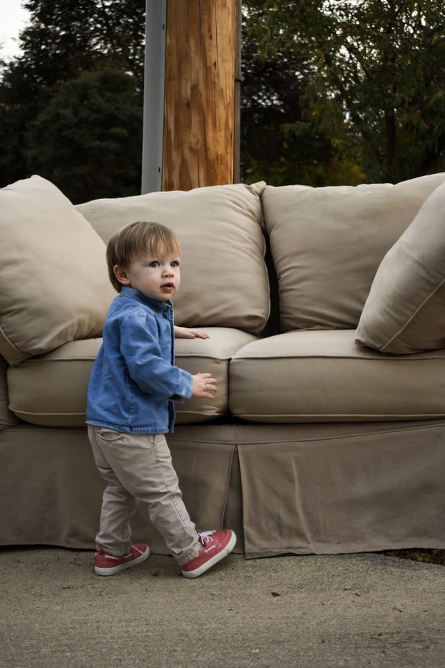 Cute 19 month toddler boy in blue denim shirt playing outdoors 