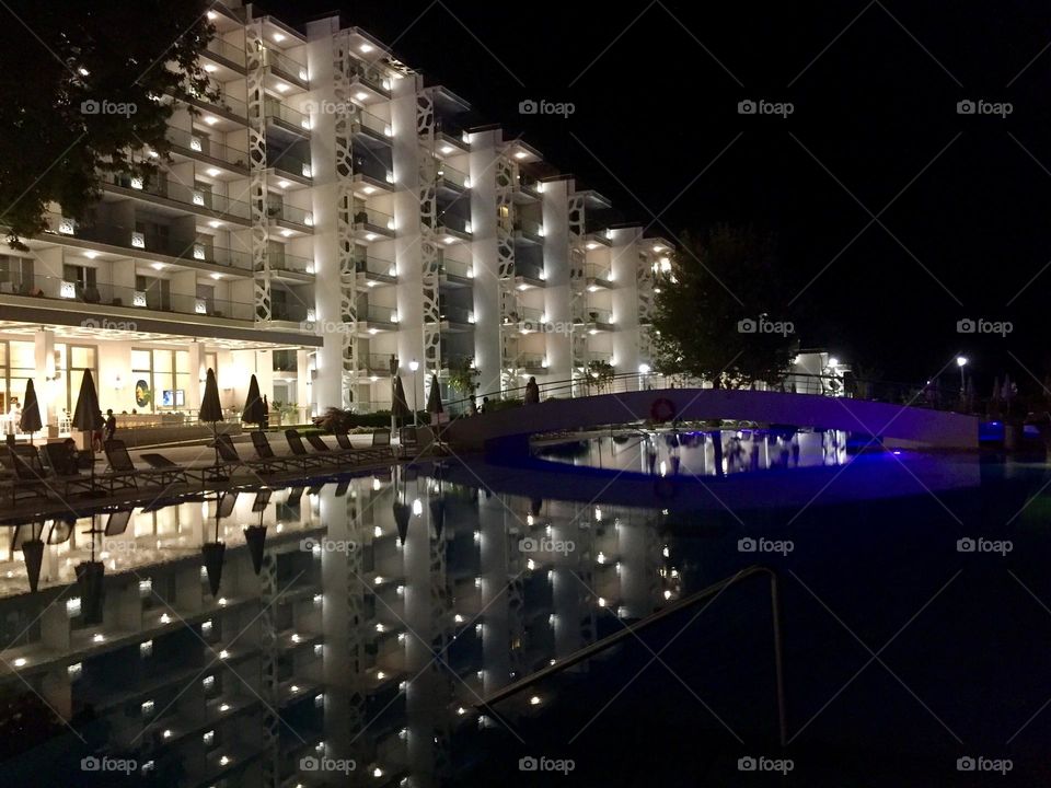 Building with illuminated windows and reflections at the pool