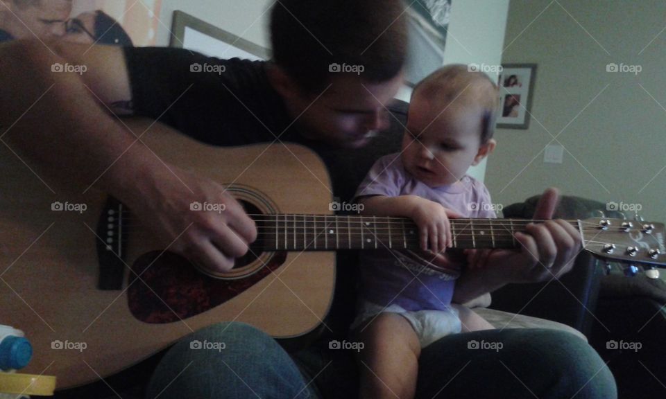 Little Strummer Girl. Playing guitar on her father's knee.