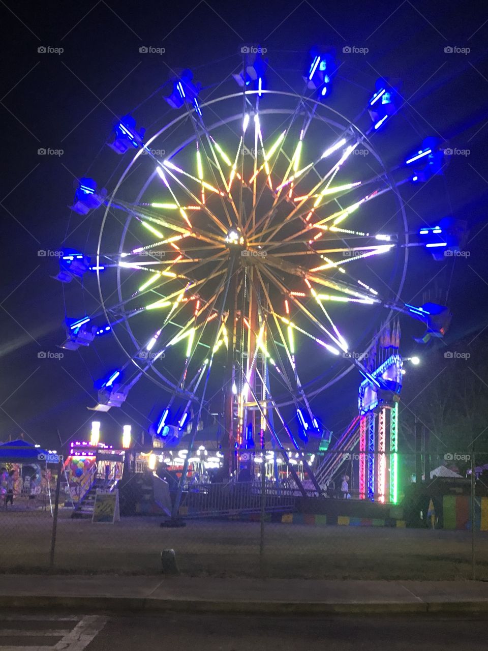 A blue and yellow lit up Ferris wheel at night boasting of fun and colors. 