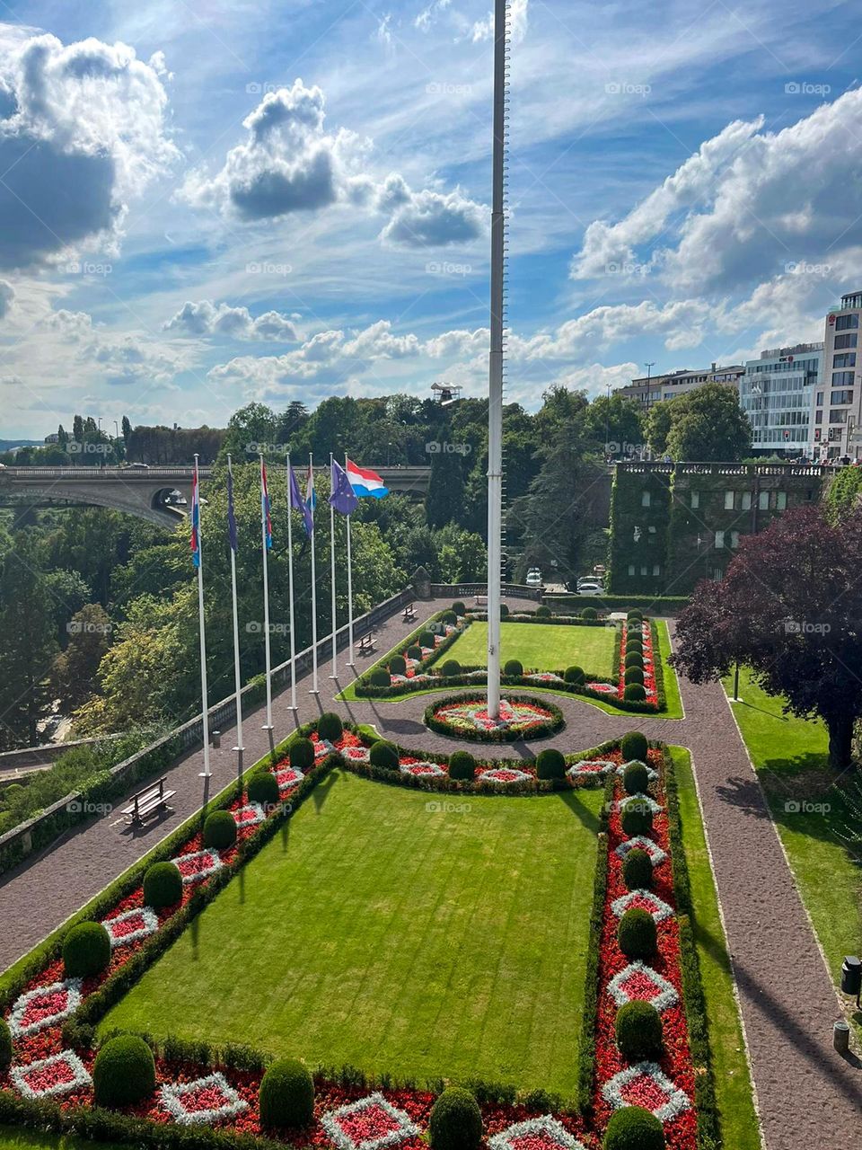 Beautiful view of the urban landscape with a green lawn, flowers and trees on a clear sunny day in Luxembourg, etc. from above close-up. Urban plants concept.