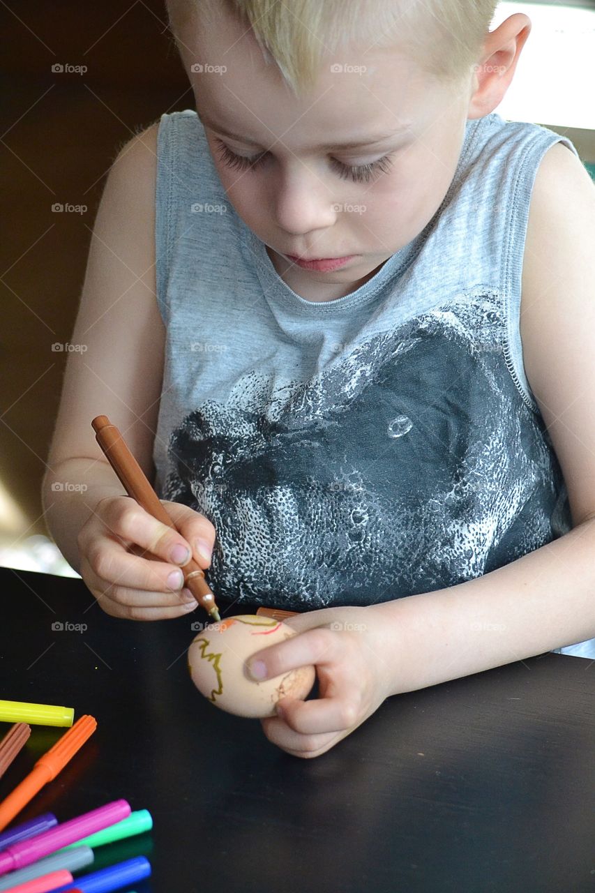 Boy painting easter eggs