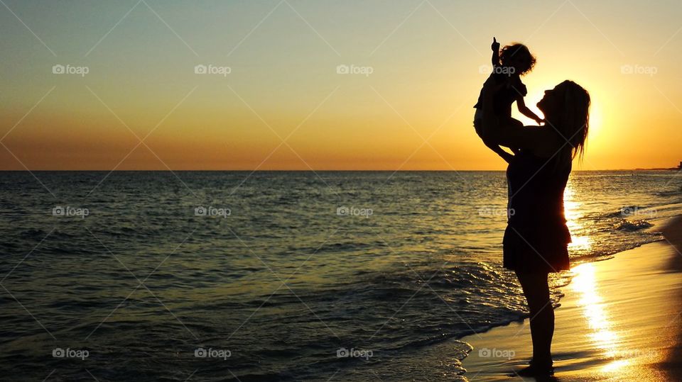 Fun day at the beach. Mom and a baby enjoying the sand and sun