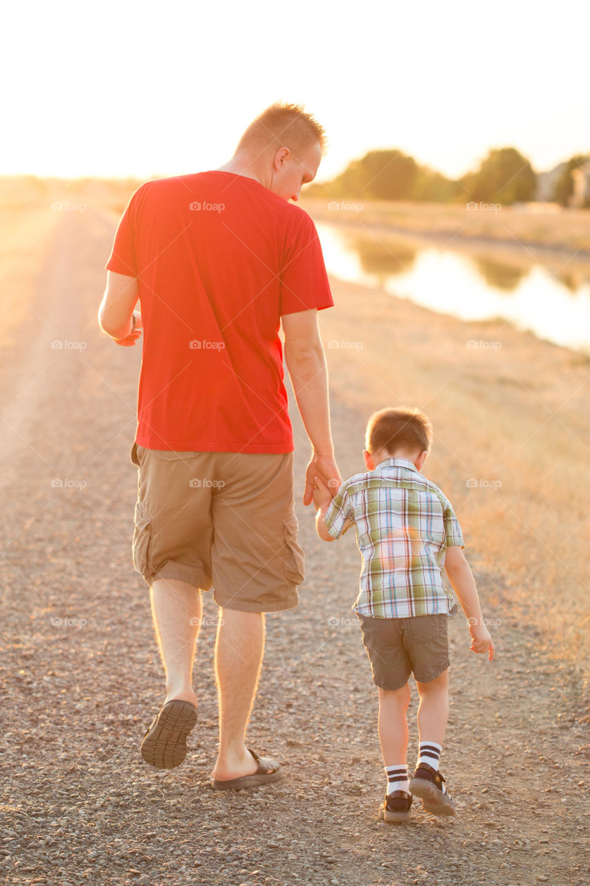 Father and son walking away in the sunset 