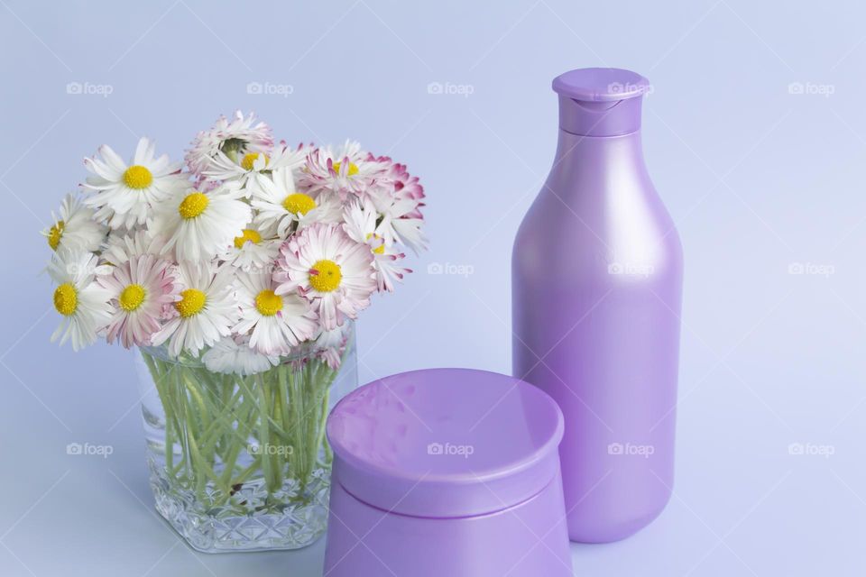 Jars with cosmetic products, beauty cosmetics in purple jars with fragrant flowers.