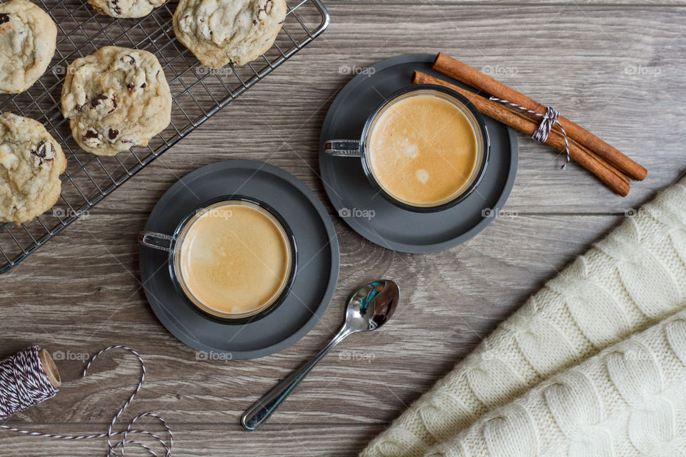 Two cups of espresso styled with cookies and a warm blanket