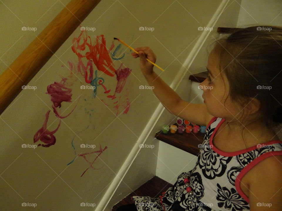 Mischievous Artist. Little girl, painting on a wall