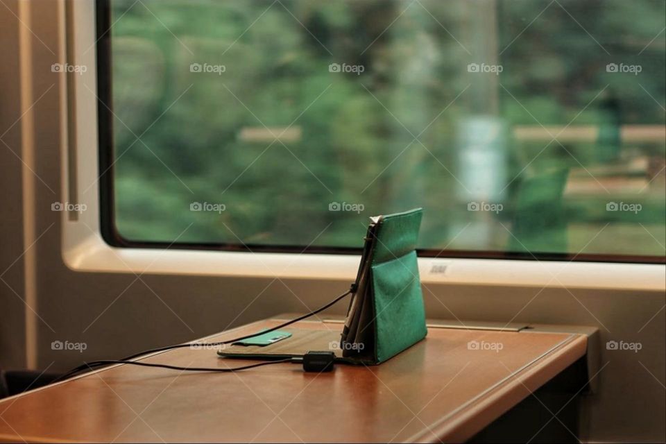 A notebook on a table in front of a train window while commuting to work on the train