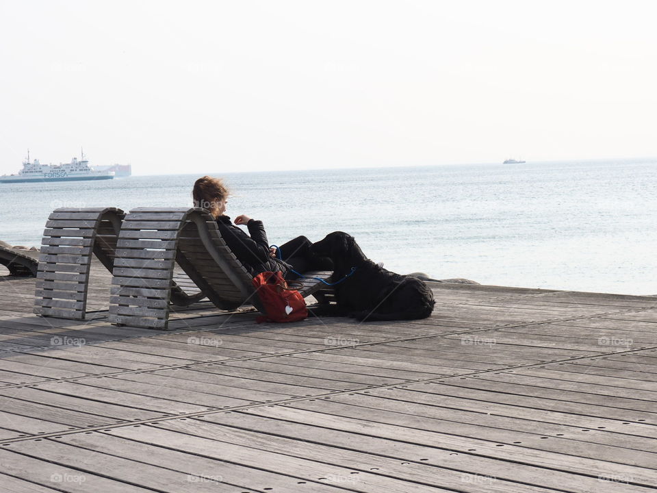 Girl with black dog on a sunny day at the coast in Helsingborg, Sweden.