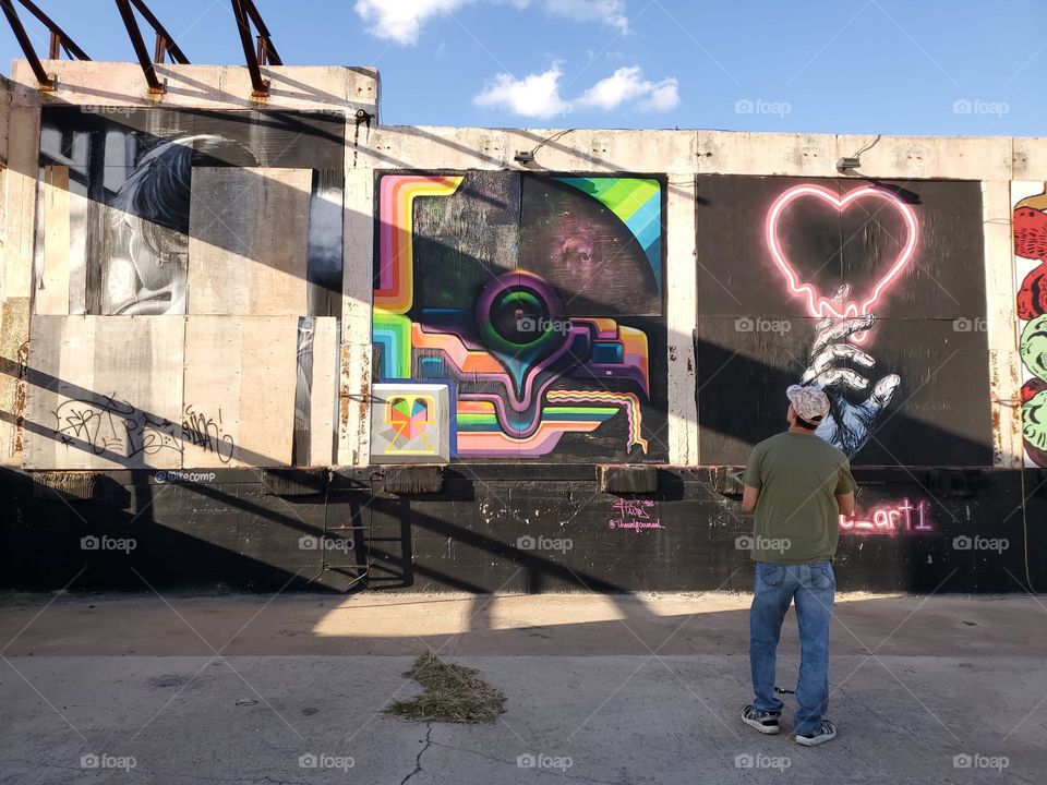 A man admiring the art at an abandoned urban outdoor art gallery.