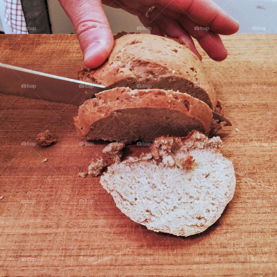 Cutting bread on a wooden cutting board 