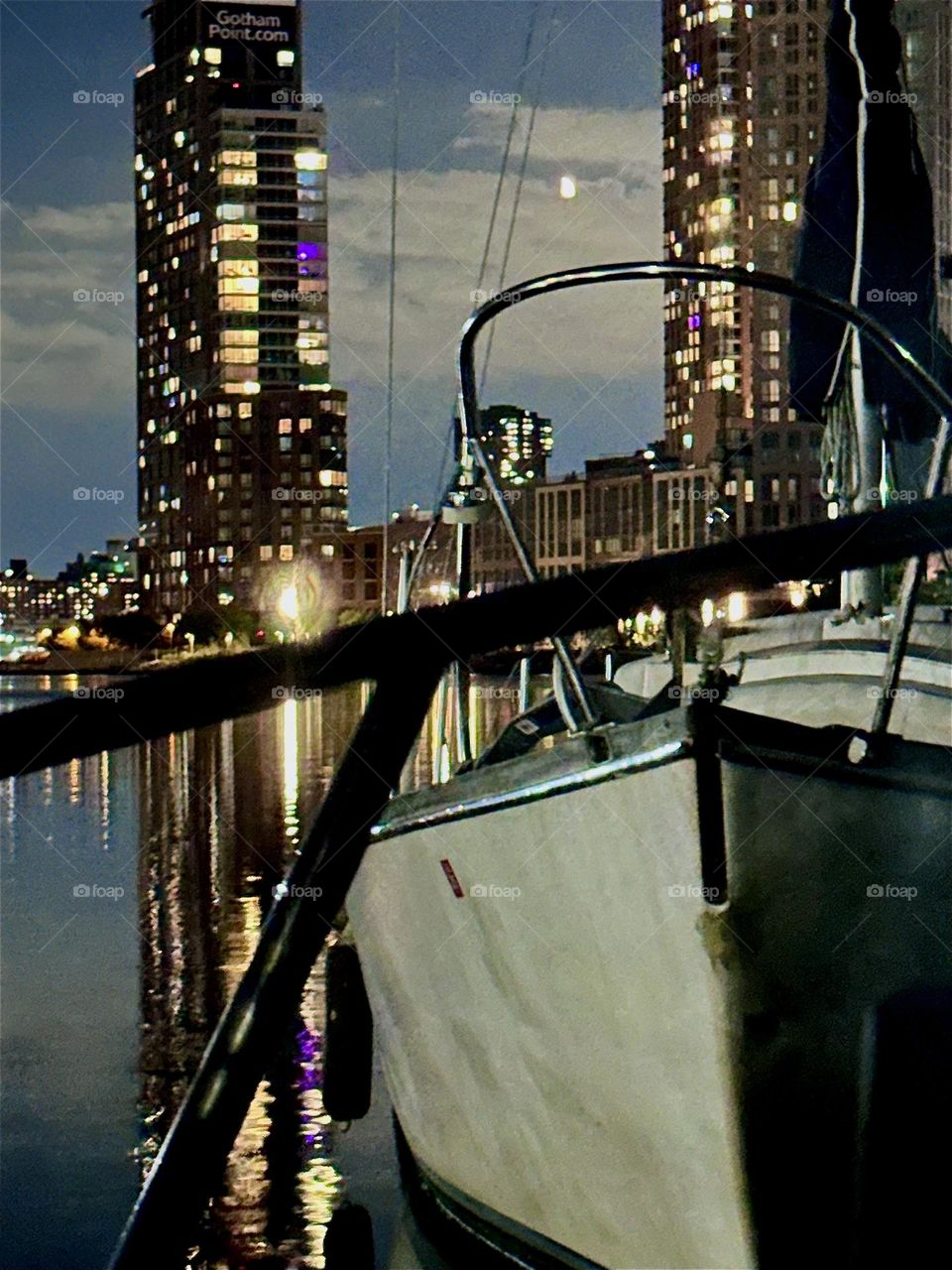 At night the boats at „Newtown Creek“ in LIC, Queens gleam in the soft moonlight. They are illuminated also by the electric lights of the high rises in LIC and “Greenpoint”, Bklyn and their reflections in the “East River”. 2024. Hypnotic Productions