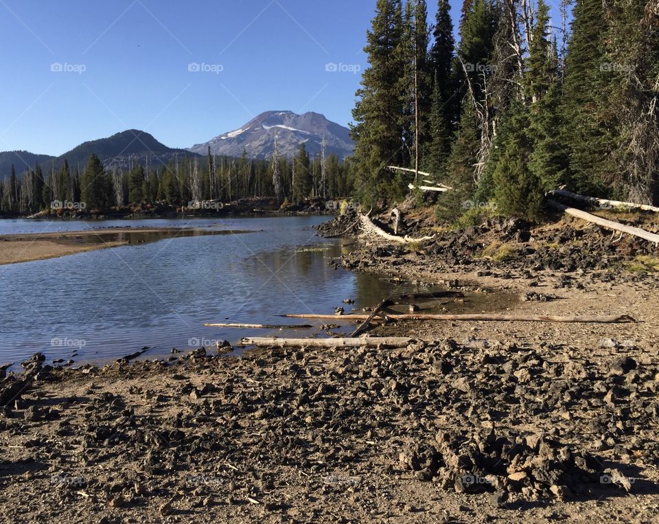 The rocky shore of Sparks Lake in Oregon's Cascade Mountains with the South Sister in the background on a sunny fall day. 