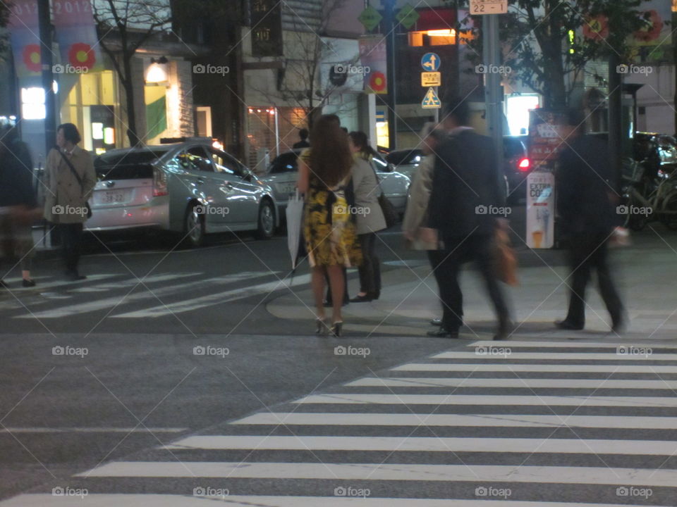 Tokyo, Japan.  Fashionable People Crossing a Street with Traffic.  Night View.