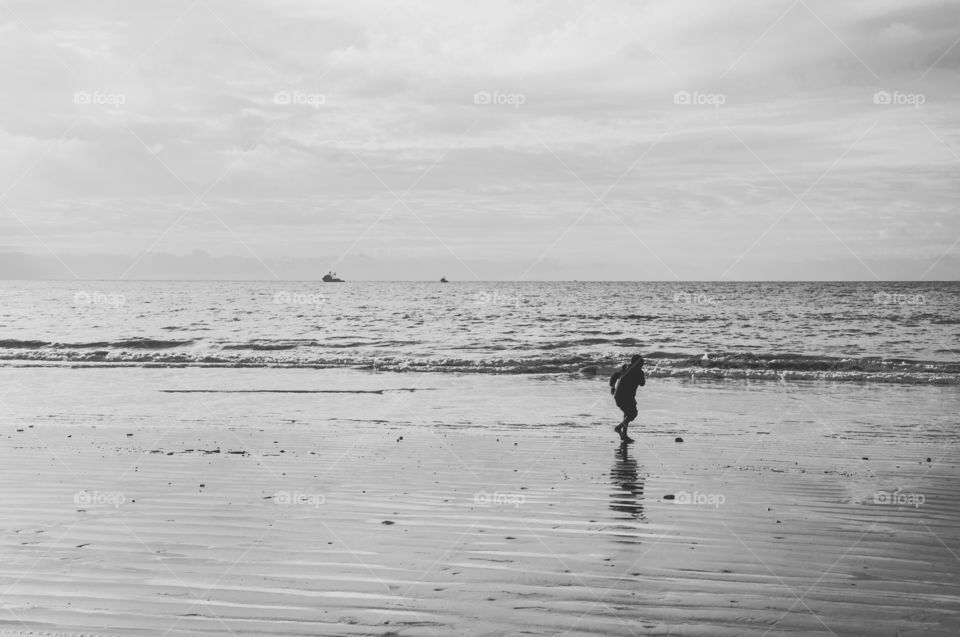 A child playing on the beach in black and white 