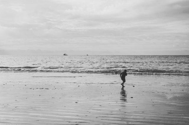 A child playing on the beach in black and white 
