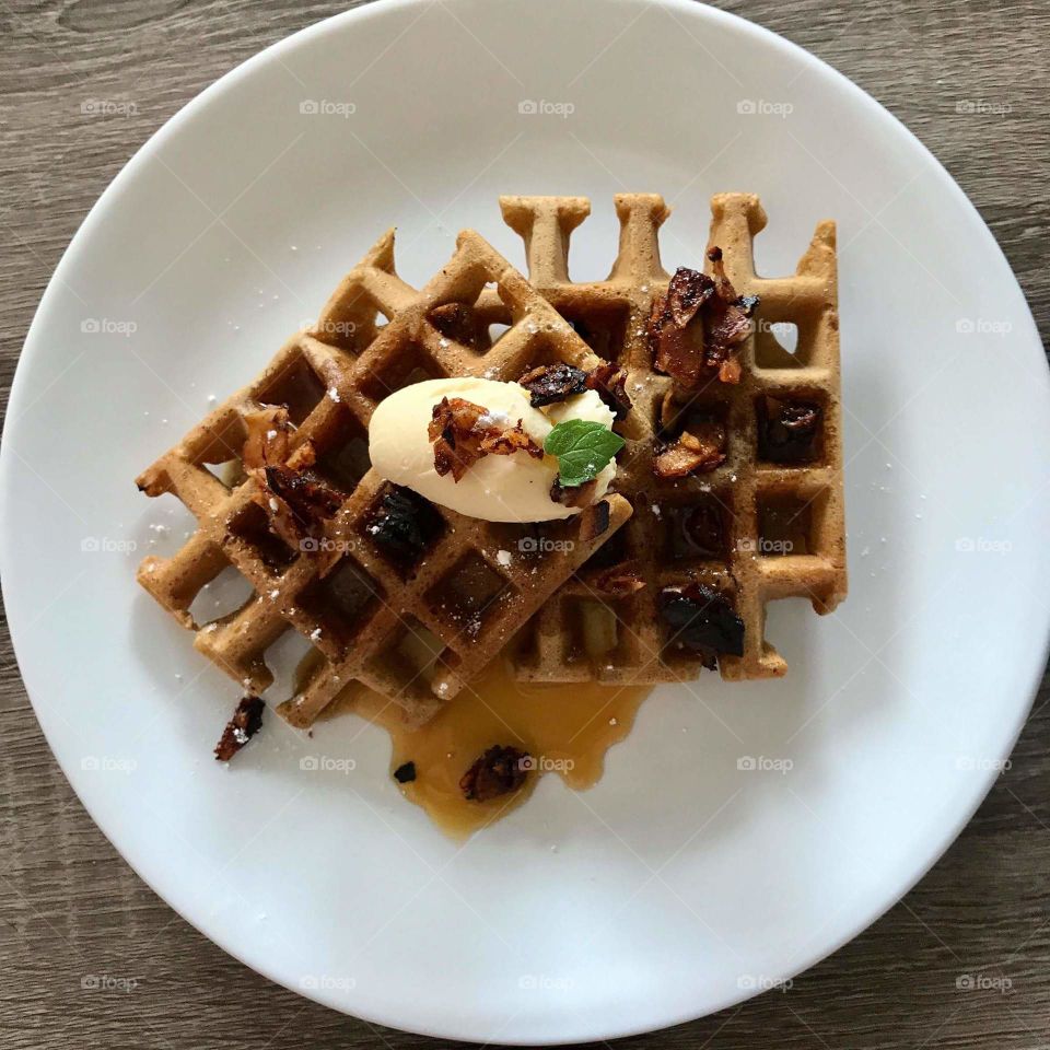 Vegan waffles with coconut bacon on white plate with wood table 