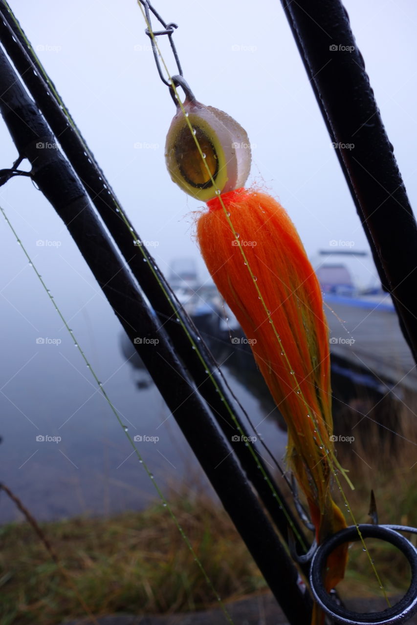 Pike fly and fishing gear. Pike fishing fly, rods, fishing line and boat on a foggy morning in Autumn