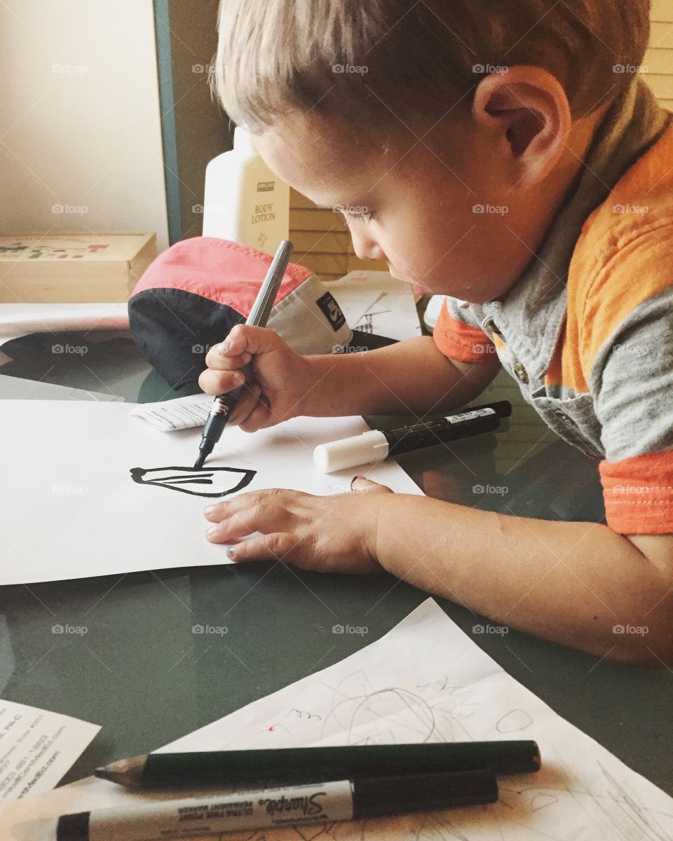 Boy drawing on paper with marker