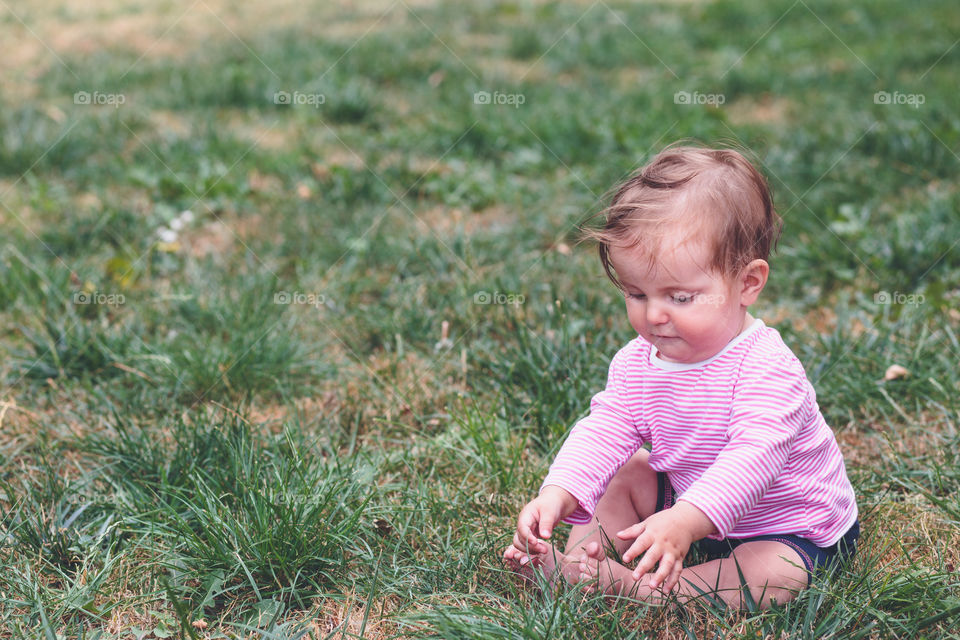 Little baby in the garden. Baby girl sitting on a grass in the garden