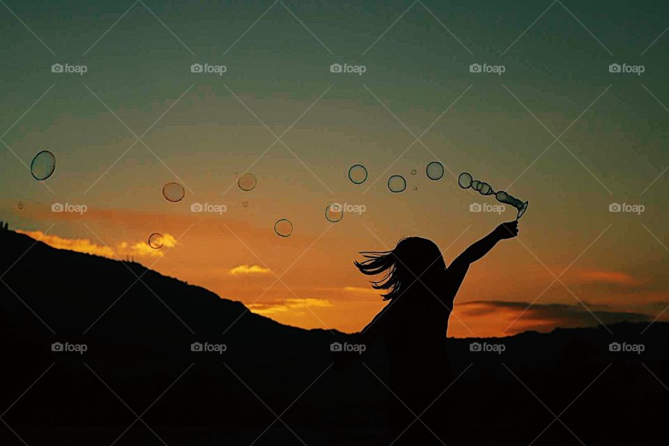 Silhouette of a girl playing with bubbles.