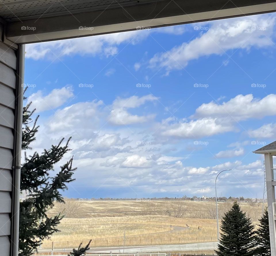 Nice white fluffy clouds in this prairie landscape framed by my deck 