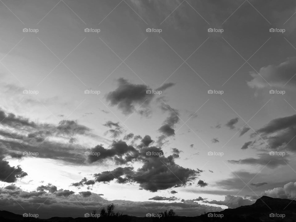 A black and white photo of a cloudy sky and a mountain.