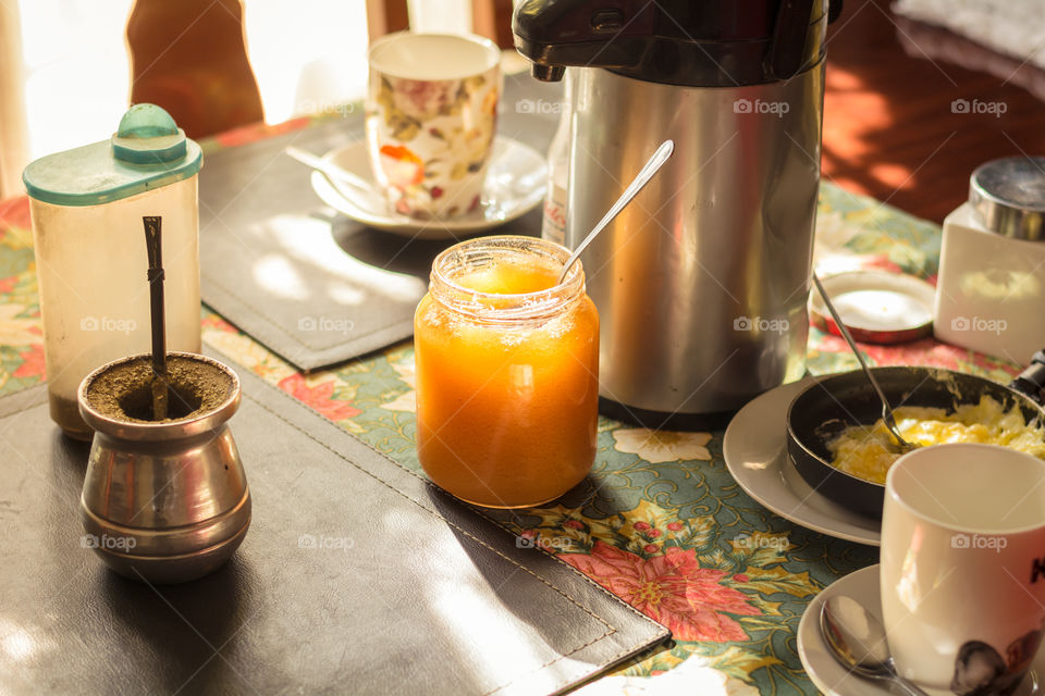 Table prepared for breakfast with honey, eggs, tea cups and mate 
