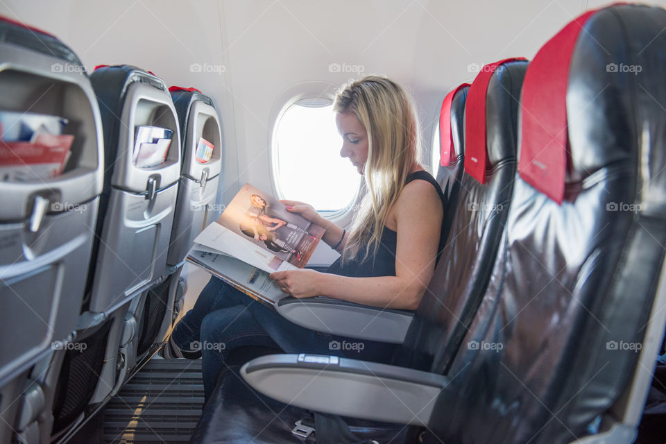 Woman reading the Tax Free catalog on a airplane.