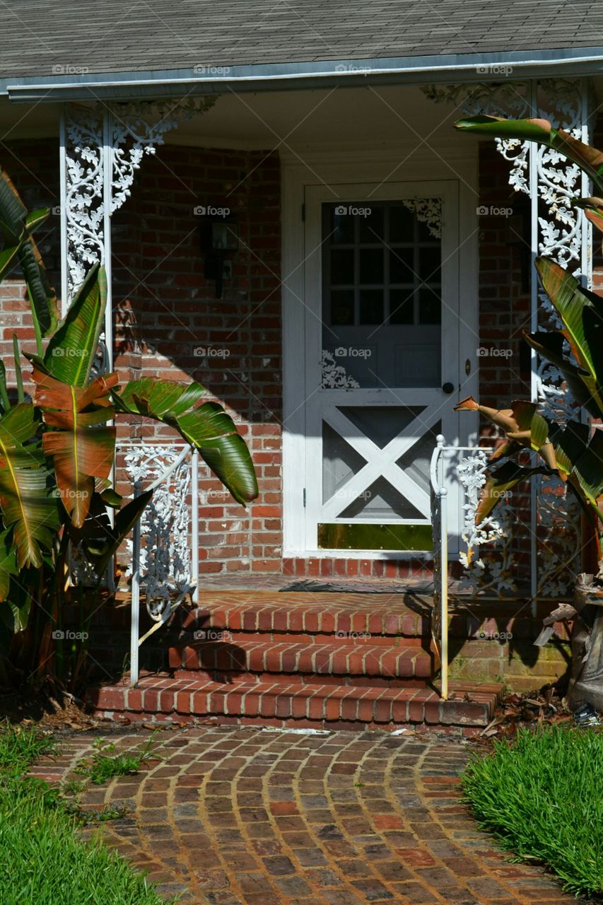entranceway of brick cottage. white ironwork and red brick cottage front doorway