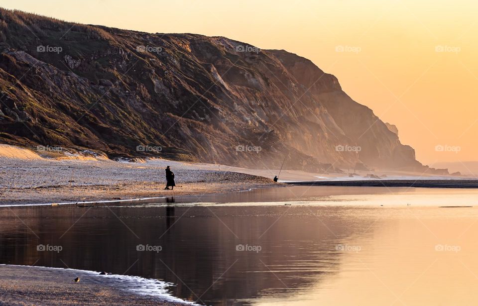 People watch the winter sunset on the beach at Pataias, Portugal 