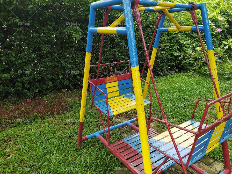 Colorful swing with a background of plants and grass, children's playground