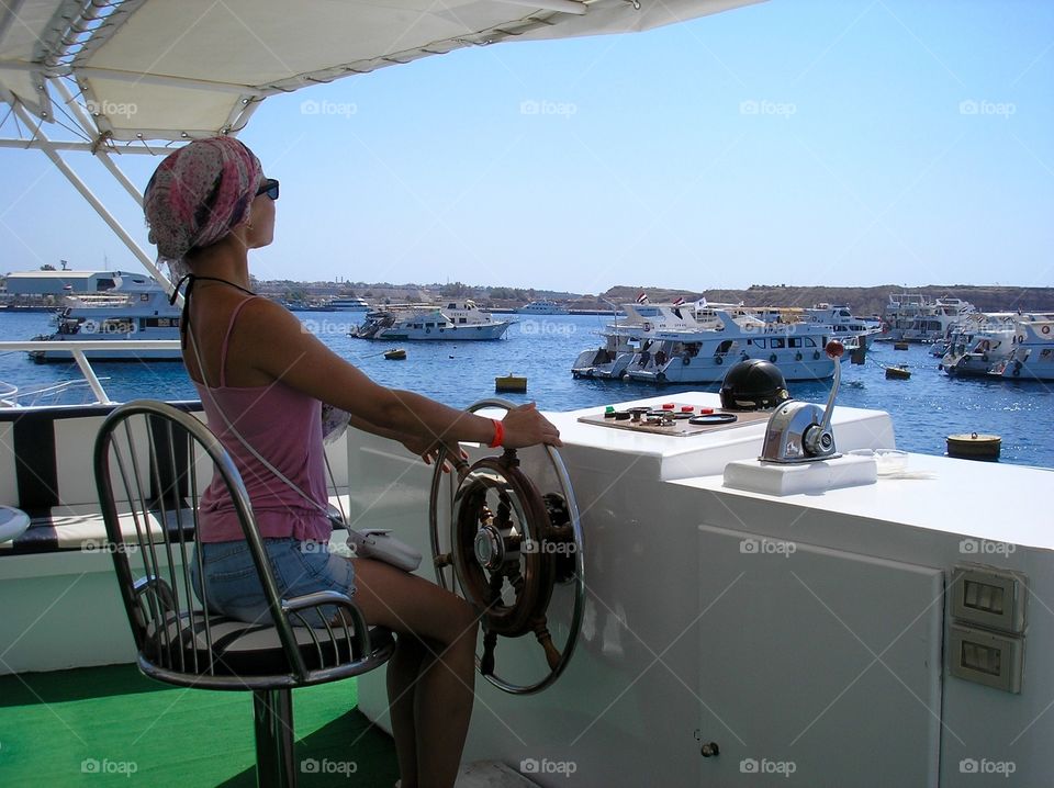 Girl captain at the steering wheel in a sailboat