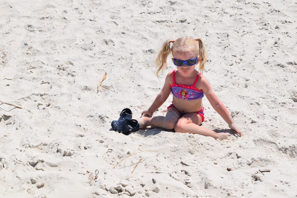 Girl playing in the sand. Toddler sitting in the sand