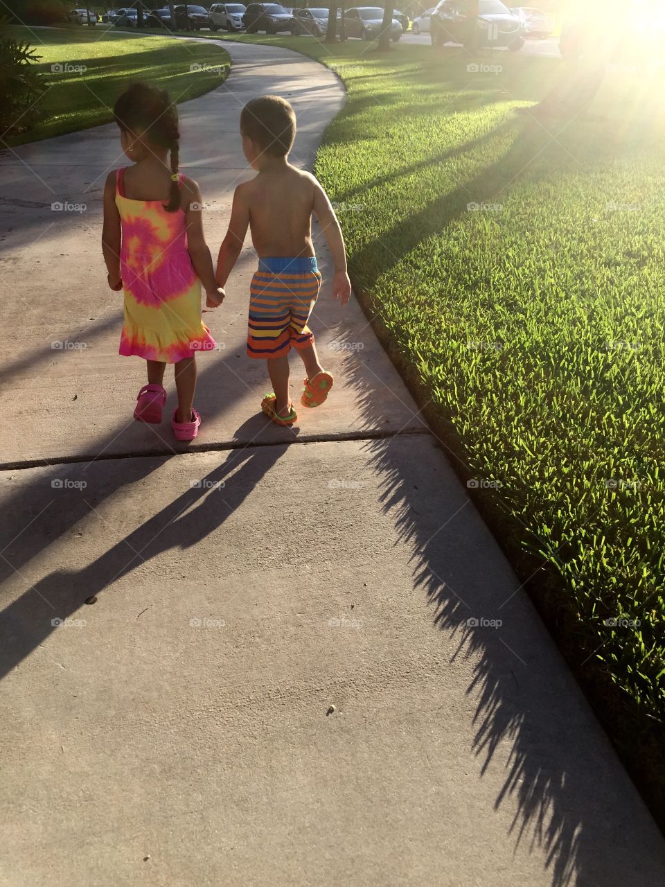 Friendship. Two children walking on pathway at sunset