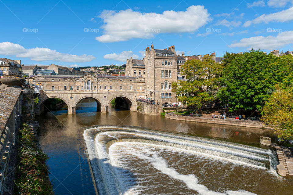 City of Bath. Town built of stones. Pulteney Bridge on River Avon with cascading waterfall. One of only four bridges to have shops. UK.