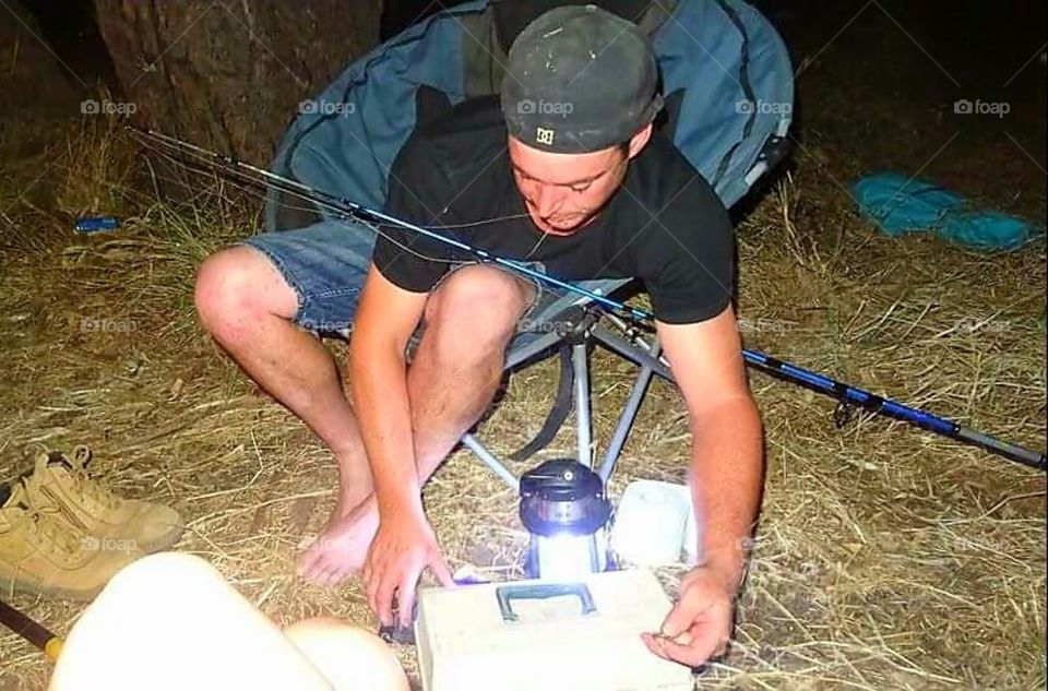 Man getting his fishing rod ready, camping adventures