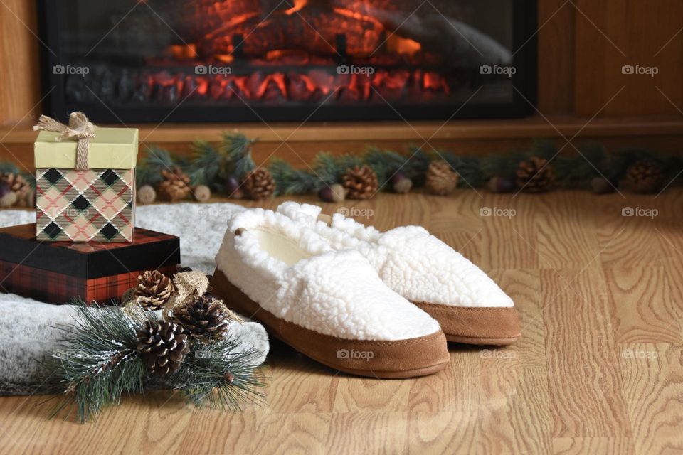 Christmas gifts sitting by slippers by the fireplace 