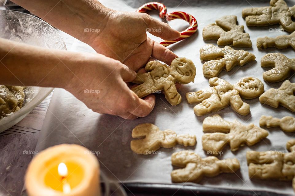 Craft product homemade Christmas cookies in the shape of men, holiday, candle and hands in the frame