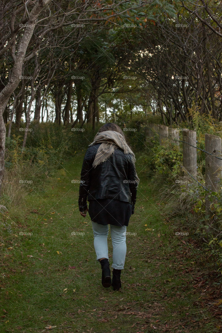 A young woman walking through a dark forest on a trail