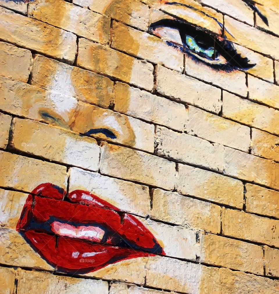 Woman's face with red lips painted on a brick wall