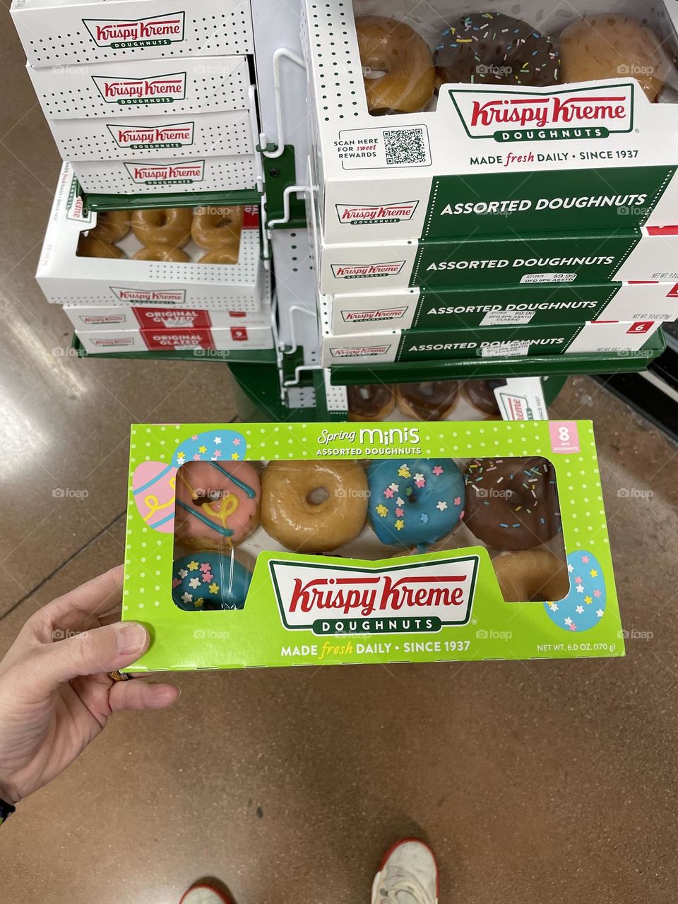 Woman’s hand holds box of Krispy Kreme donuts, buying donuts at the store, picking out donuts at the grocery store, shopping for donuts